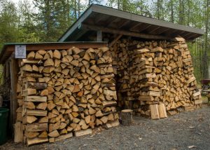 a pile of logs in front of a brick building