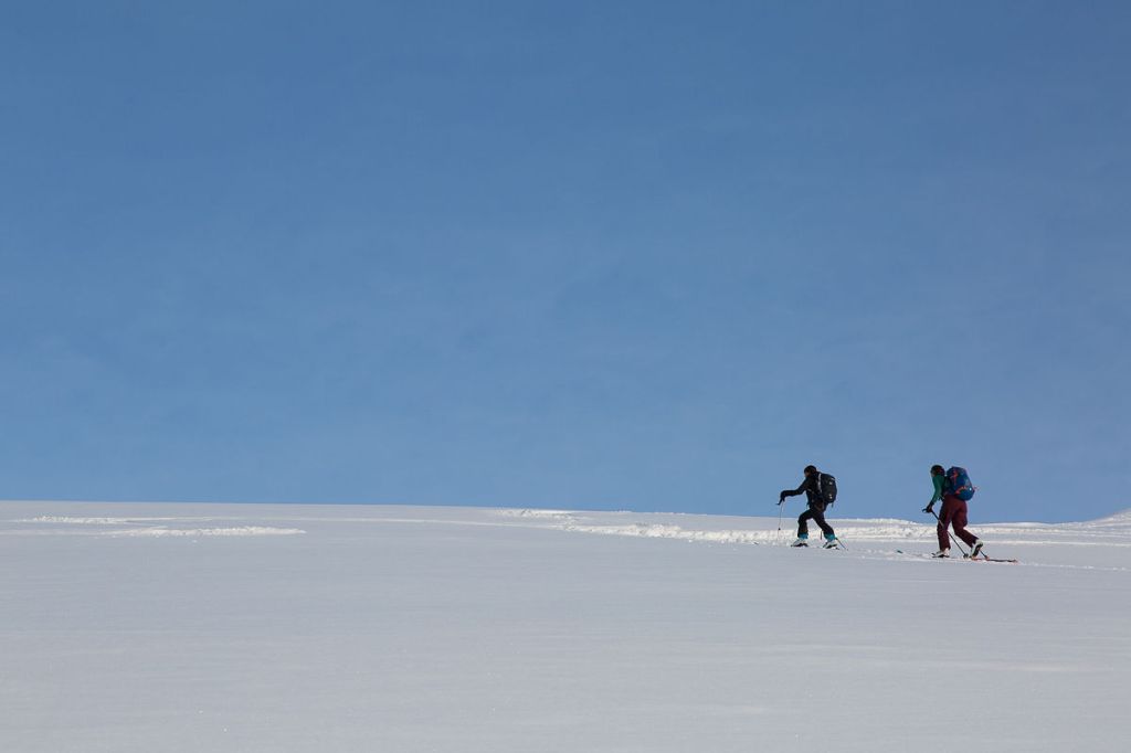 a group of people riding skis down a snow covered slope